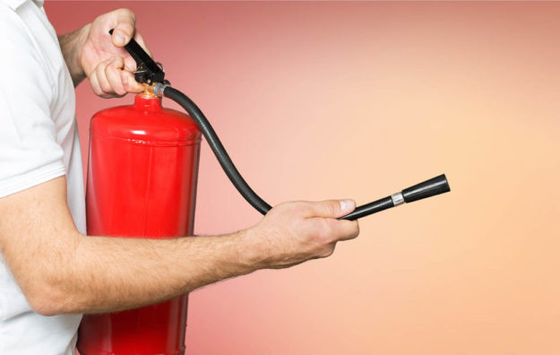 Man using fire extinguisher against grey background